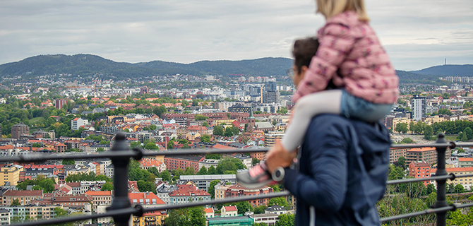 Voksen person med barn på skuldre som sammen ser utover Oslo.